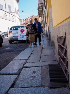 Cremona, İtalya - 27 Mayıs 2024 Yaşlı çift emekliliğin tadını çıkarıyor, büyüleyici İtalyan sokaklarında geziniyorlar, sıcak güneş ışığında güneşleniyorlar, aktif yaşlıların neşesini somutlaştırıyorlar