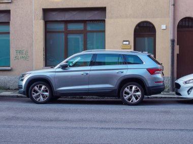 Cremona, İtalya - 27 Mayıs 2024 Skoda Konjac Silver SUv, bir binanın önündeki dar bir sokağa park edilmiş, arkasında bedava bir balçık grafitisi var, komik bir kontrastlık sağlıyor.