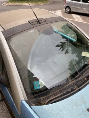 Cremona, İtalya - 9 Haziran 2024 Tozlu mavi araba bir kum fırtınasından sonra bir çöl parkına park edilmiş, havanın taşımacılık üzerindeki etkisini ve kirli bir ortamda temizlik ihtiyacını gösteriyor