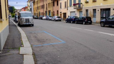 Boş park yeri, asfalt caddesinde mavi boyayla işaretlenmiş park edilmiş arabalar ve eski model minibüslerle.