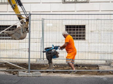 Cremona, İtalya - 10 Haziran 2024 İnşaat işçisi bir şehir caddesinde asfalt kırmak için kaya matkabı kullanıyor