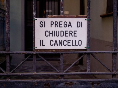 Cremona, İtalya - 10 Haziran 2024 Paslı metal bir çite asılmış İtalyanca kapı levhasını kapat