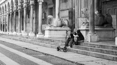 Cremona, İtalya - 10 Haziran 2024 Genç çift tarihi bir mekanda birbirlerine eşlik ederek antik merdivenlerde mola veriyorlar.