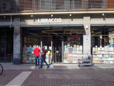 Cremona, İtalya - 10 Haziran 2024 Libraccio italyan kitapçısının önünde şehir merkezinde büyük pencereli iki adam kitap okuyor.