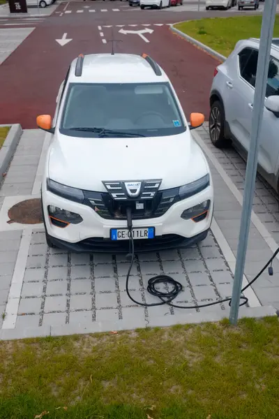 Cremona, İtalya - 15 Haziran 2024 Dacia White elektrikli otomobili şehir ortamında bir kamu şarj istasyonunda şarj oluyor.