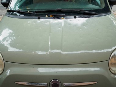 Cremona, İtalya 19 Temmuz 2024 Yeşil araba şehir caddesinde park halinde. Kaputu birden fazla göçükle dolu fırtınasından dolayı büyük hasar görmüş.