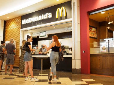 Cremona, İtalya 19 Temmuz 2024 Müşteriler kalabalık bir alışveriş merkezinde McDonald 's' ın tezgahından yemek sipariş ediyorlar.