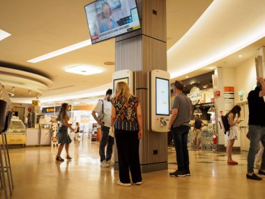 Cremona, İtalya 19 Temmuz 2024 Müşteriler siparişlerini bir alışveriş merkezinin yemek bölümünde dijital self servis büfesinden alıyorlar.