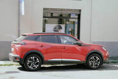 Cremona, İtalya - 15 Temmuz 2024 Kırmızı kompakt Peugeot SUv arabası güneşli bir yaz gününde şehrin dar bir sokağında park edilmiş, otomotiv temaları veya kentsel yaşam temalarını sergilemek için ideal