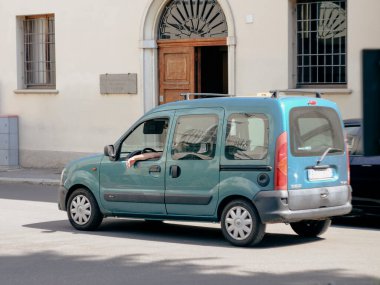 Cremona, İtalya - 15 Temmuz 2024 Güneşli bir günde yeşil minivan Renault Kangoo kullanan adam, özgürlük ve maceranın tadını çıkarıyor