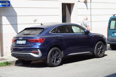 Cremona, İtalya - 15 Temmuz 2024 Mavi SUV Audi Q3 bir şehir caddesinde önünden geçen bir adamla park edilmiş, şehir cazibesini Avrupa 'nın lüks manzarasıyla harmanlayan