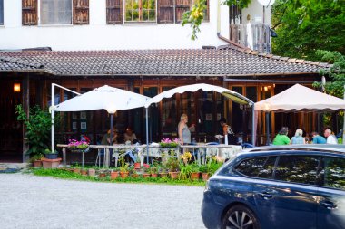 Morfasso, İtalya - 15 Temmuz 2024 Bir yaz akşamı büyüleyici bir restoranın terasında akşam yemeğinin tadını çıkaran insanlar, sıcak, davetkar bir atmosferde yemek, içmek ve sosyalleşmek. 