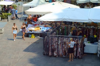 Parma, İtalya 24 Temmuz 2024 Alışverişçiler hareketli bir yaz gününde hareketli bir açık hava pazarında renkli kıyafetlere göz gezdiriyorlar. Ucuzluk arıyorlar ve gardıroplarına stil katıyorlar.