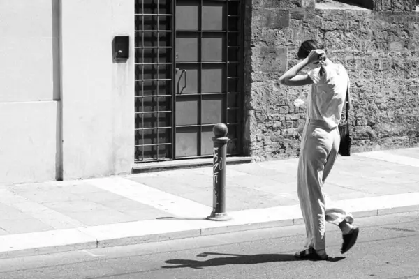 stock image Parma, Italy July 24th 2024 A young woman is adjusting her hair while walking down a city street on a sunny afternoon