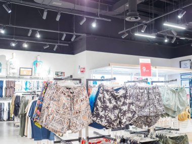 Cremona, İtalya 29 Temmuz 2024 Bir giyim mağazası yaz sezonu için yeni renkli kıyafetler ve yüzme şortları koleksiyonu sergiliyor