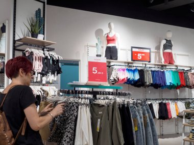 Cremona, İtalya 29 Temmuz 2024 Kızıl saçlı kadın bir moda mağazasından elbise seçiyor.