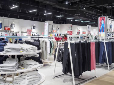 Cremona, İtalya 29 Temmuz 2024 Modern moda mağazası iç tasarımı. Mankenler yeni kıyafet koleksiyonunu gösteriyor. Mağazada bir müşteri yürüyor.
