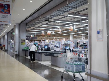 Cremona, İtalya 29 Temmuz 2024 Bir kasiyer ön planda su şişeleriyle dolu bir alışveriş arabasıyla süpermarketin kasasını tarıyor