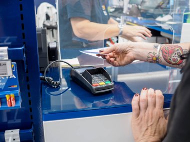 Cremona, İtalya 29 Temmuz 2024 'te bir müşteri kredi kartıyla arka planda kasiyer olan bir mağaza kasasından ödeme yapıyor.