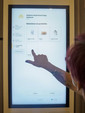 Cremona, İtalya 29 Temmuz 2024 bir kadın fast food restoranından yemek sipariş ederek dijital menüden bir şeyler seçiyor.