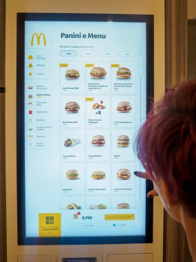 Cremona, İtalya 29 Temmuz 2024 Bir kadın fast food restoranından yemek sipariş etmek için dijital self servis panelini kullanıyor