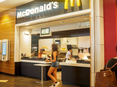 Cremona, İtalya 29 Temmuz 2024 genç bir kadın yemek siparişi verdikten sonra McDonald 's restoranından bir paket ile ayrılıyor.