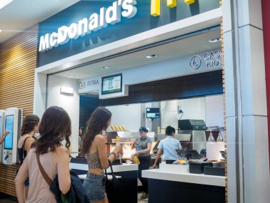 Cremona, İtalya 29 Temmuz 2024 Aç Müşteriler McDonald 's restoranından fast food sipariş ediyorlar. Çeşitli seçenekler arasından seçim yaparak ve avroyla ödeme yaparak, çeşitli insanlarla modern iç mekanlar