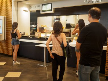 Cremona, İtalya 29 Temmuz 2024 bir aile modern bir restoran tezgahında hazır yemek bekliyor. Aç ve heyecanlılar, başkalarıyla sıra oluyorlar, birlikte yemek yemek için sabırsızlanıyorlar.