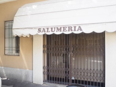 Cremona, İtalya 29 Temmuz 2024 Kapalı kapısı ve tenteli İtalyan salatalık dükkânı önü, salgın sırasında terk edilmiş, gölgeler ve güneş ışığıyla sakin bir sahne yaratmış.