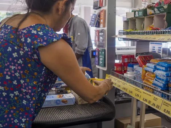 stock image Cremona, Italy July 29th 2024 Woman wearing a blue dress checking the price tag of a product on a shelf in a supermarket