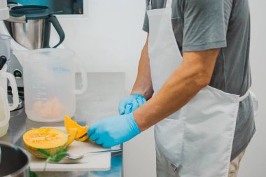 Modern bir mutfakta şef, sağlıklı yemek hazırlama konusunda profesyonel yeteneklerini sergileyen hassas ve hijyenik taze bir kavun hazırlar.