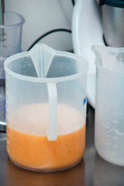 Taze sıkılmış portakal suyu mutfak tezgahındaki plastik ölçü kabında, sağlıklı bir sabah kahvaltısı için mükemmel.