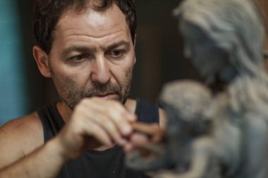 Heykeltıraş ahşap bir parça oymak için bir keski kullanıyor, güzel ahşap bir heykel yapıyor.