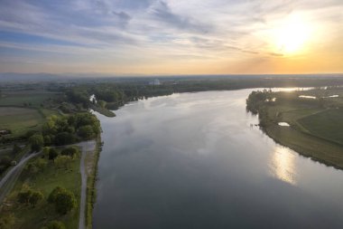 Gün batımında sakin çakıl yolu, sakin sulara yansıyan altın ışıkla birlikte, sakin bir manzara yaratıyor, Po Nehri, Piaceza, İtalya