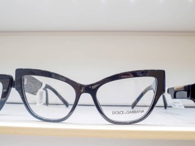 Bir optometristin ofisindeki beyaz bir rafta duran siyah plastik çerçeveli gözlük.