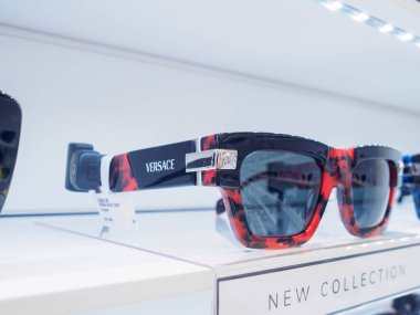Kırmızı ve siyah versace mermer desenli güneş gözlükleri optik bir mağazadaki bir rafta sergilenir.
