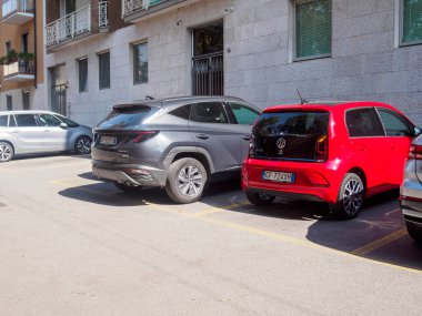 Cremona, İtalya 31 Ağustos 2024 güneşli bir günde düzgün park edilmiş araçlar, arka planda binalarla birlikte boş bir arsaya paralel dizilmiş.