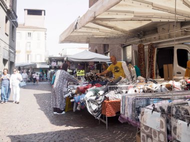 Cremona, İtalya 31 Ağustos 2024 bir kadın İtalya 'daki bir tezgahtardan tekstil pazarında kumaş seçiyor.