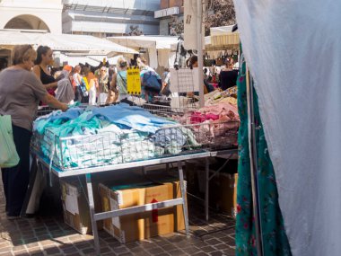 Cremona, İtalya 31 Ağustos 2024 bir kadın İtalya 'daki bir tezgahtardan tekstil pazarında kumaş seçiyor.