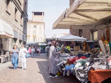 Cremona, Italy August 31st 2024 A woman is choosing fabric at an outdoor textile market from a stall holder in italy clipart