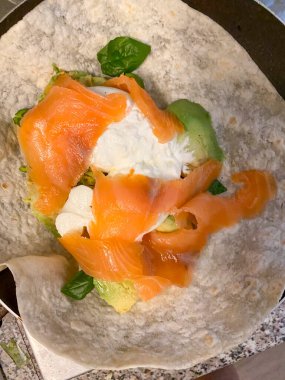 Üstünde somon ve avokado olan bir burrata piadina.