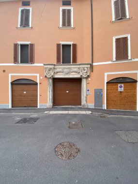 Cremona, İtalya 19 Temmuz 2024 3 garaj kapısı eski bir İtalyan binasının zemin katına, 2 'si ahşap tahta kapılı ve 1' i kahverengi metalik kapılı.