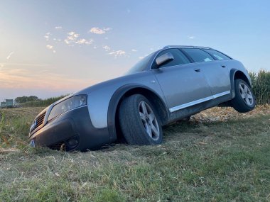 Cremona, İtalya 19 Temmuz 2024 Audi a6 allroad otomobili gün batımında vahşi bir mısır tarlasından geçtikten sonra hendeğe sıkıştı. Beklenmedik durumlarda yardıma ve sorumluluğa duyulan ihtiyacı vurguladı.