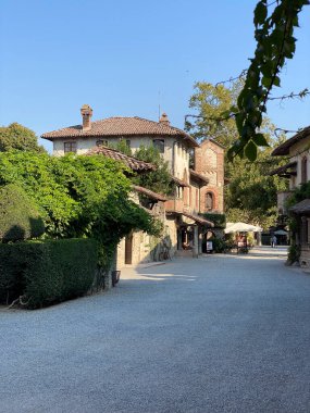 Grazzano VIsconti, İtalya 31 Ağustos 2023 Sıcak güneş ışığıyla yıkanan İtalyan köyü, terasotta çatıları ve yemyeşil yeşillikleri olan büyüleyici evlere ev sahipliği yapıyor.