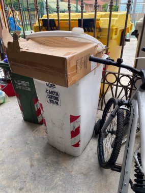 Cremona, İtalya 19 Temmuz 2024 taşan bir karton kutu kağıt için beyaz geri dönüşüm kutularının üzerinde cam için yeşil bir geri dönüşüm kutusunun yanında duruyor.