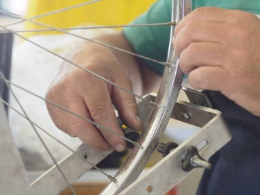 Close up of a bike mechanic's hands fixing a wheel in a workshop, showcasing precision and expertise in bicycle maintenance. Craftsmanship and dedication in skilled labor are highlighted clipart