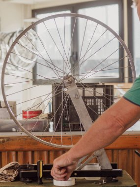 Skilled bicycle mechanic truing a wheel in a repair shop, focusing on adjusting spokes with precision. Capturing craftsmanship and dedication to bike maintenance clipart