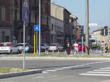 Cremona, İtalya - 19 Eylül 2023 Yoğun Sokak, yaya geçidi ve bisiklet için mavi tabela. Bir kadın karşıdan karşıya geçiyor..