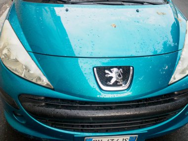 Cremona, İtalya 26 Eylül 2024 Mavi bir peugeot 207 cephesine yakın, yağmurdan sonra kaputun üzerine su damlıyor.