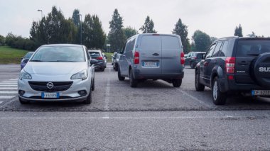 Cremona, İtalya 26 Eylül 2024 'te şehrin bulutlu bir gününde kalabalık bir otoparktan çıkmak için sabırla bekleyen çeşitli modern arabalar. Bir şehir zeminine karşı beyaz, gümüş, siyah ve gri araçlar